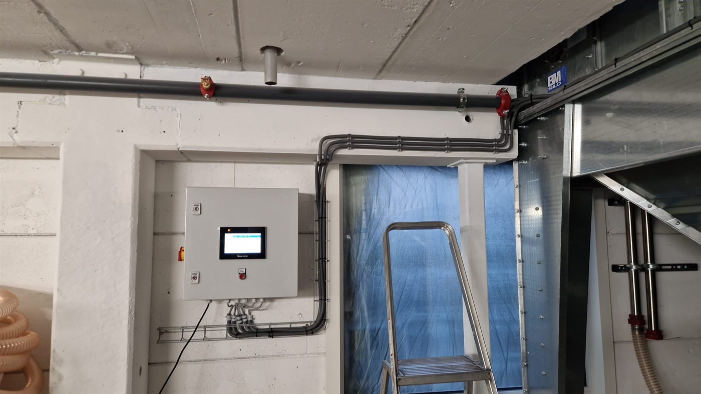 Compacte besturingskast met touchscreen voor silometing, gemonteerd op locatie naast de materiaalleidingen van een silo-installatie